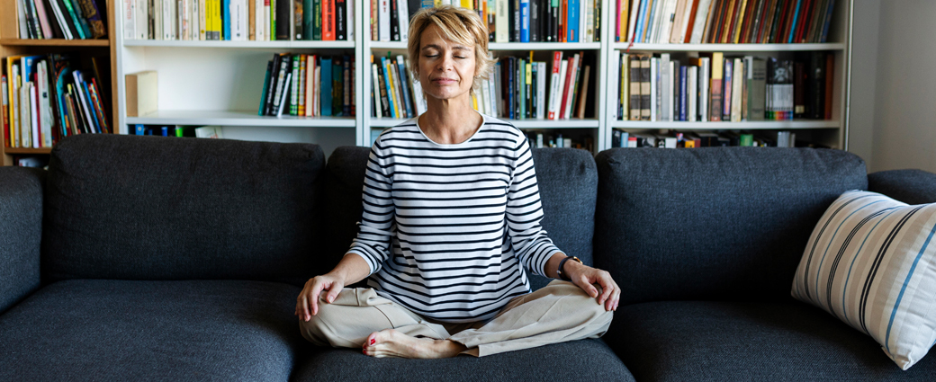 A women meditating on a couch.