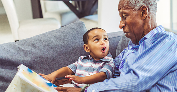 A toddler looking at an older man with a happy face