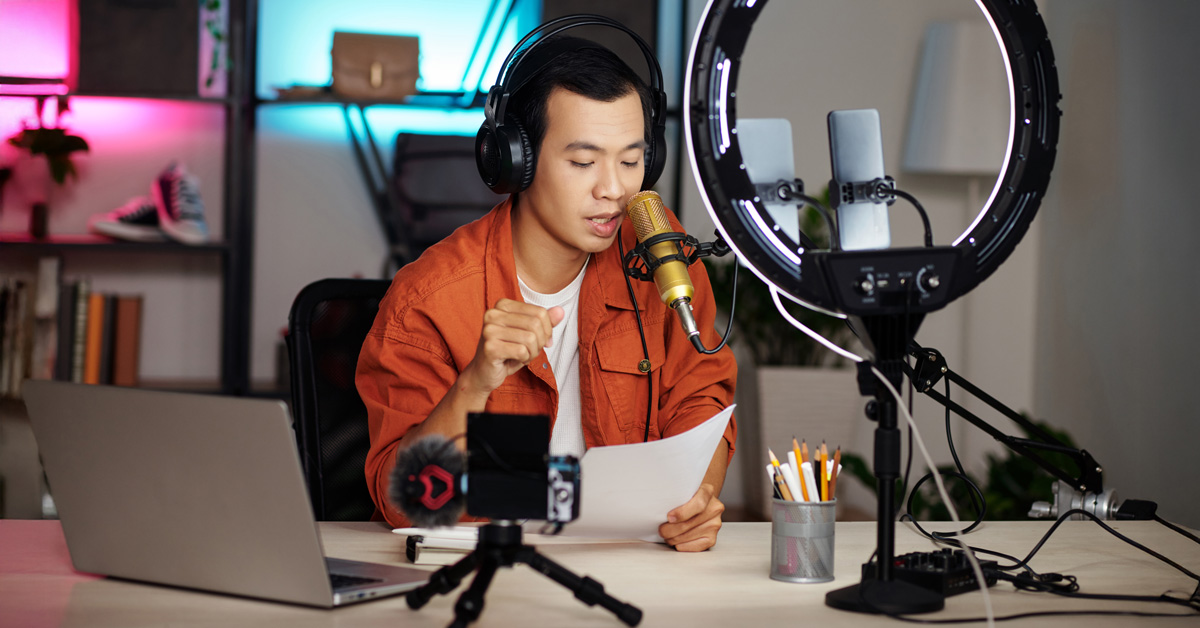 A man sitting behind a desk making a podcast