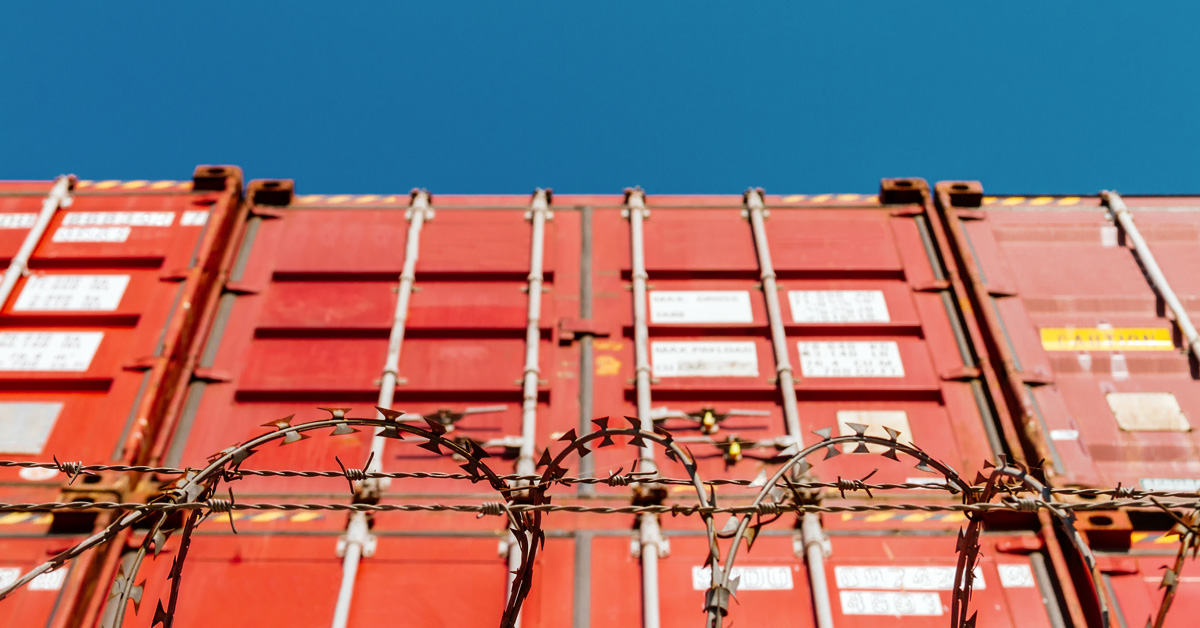 A stack of shipping containers behind a wire fence