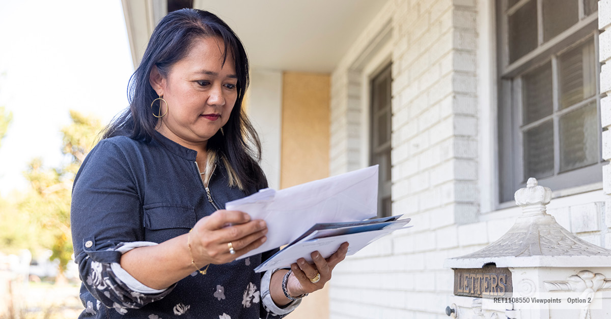 Woman standing by mailbox going through her mail
