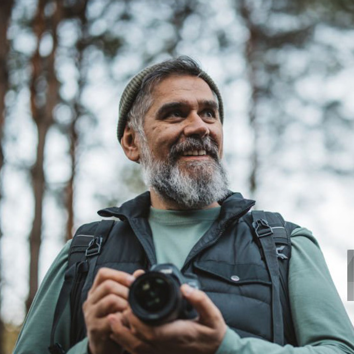 A confident young professional smiles warmly in a neutral setting, radiating positivity and approachability.