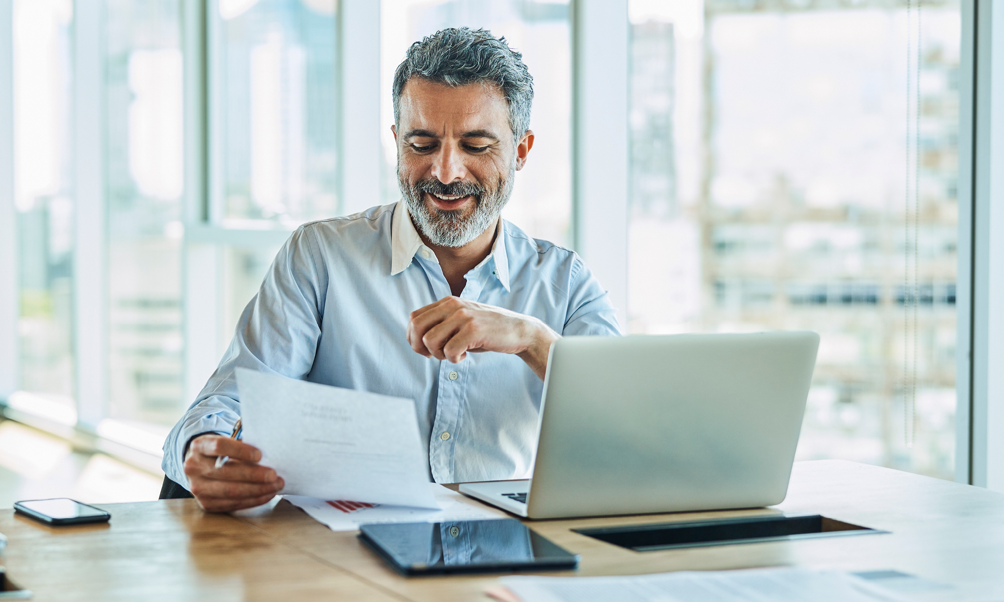 A man reviewing documents while sitting at his laptop