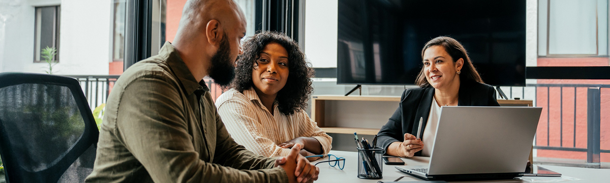 Smiling businesswoman and male colleague review data on a computer in a modern office, highlighting professional teamwork.