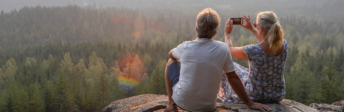 A couple overlooking the trees over a mountain