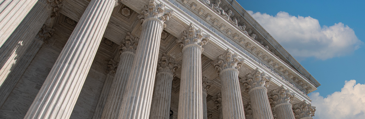 Architectural columns aligned along a street, with a bright sky providing a picturesque backdrop.