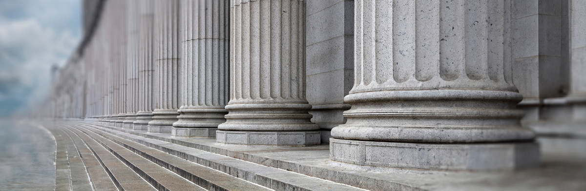 Architectural columns aligned along a street, with a bright sky providing a picturesque backdrop.