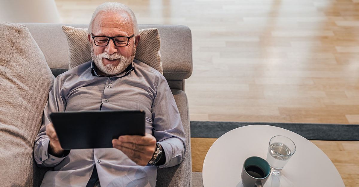 Photo of man on couch looking at laptop.