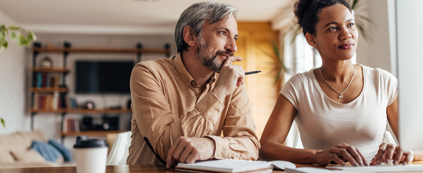 A man and woman are seated at a table, working together on a laptop, sharing ideas and information.