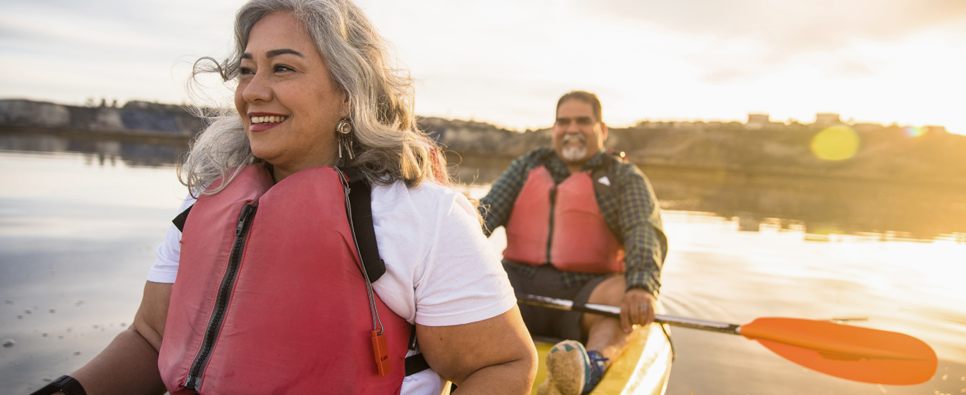 A senior couple navigates a kayak on a peaceful lake, immersed in nature and enjoying their time together.