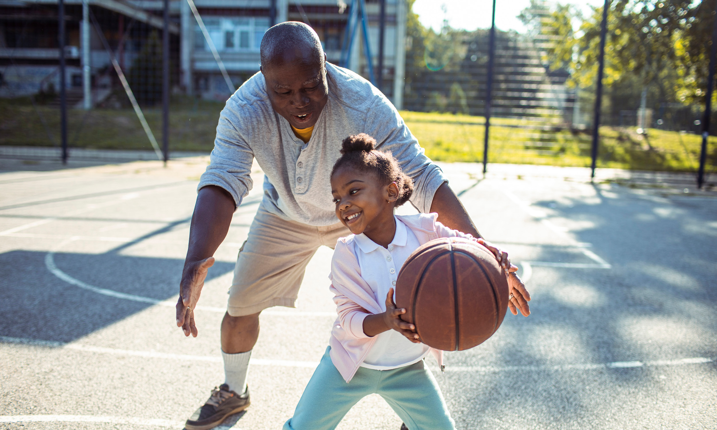 Man playing basketball with a young girl