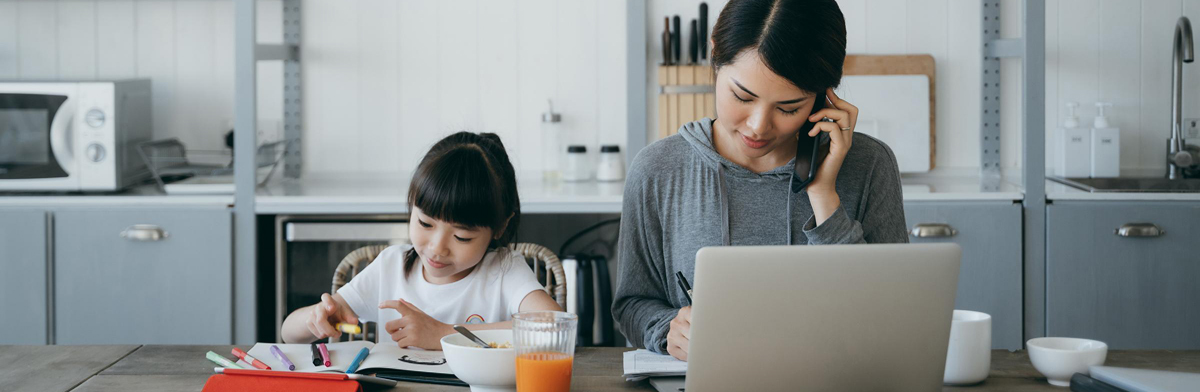  A woman and a child collaborate on a laptop in a bright kitchen, surrounded by cooking utensils and a cozy atmosphere.