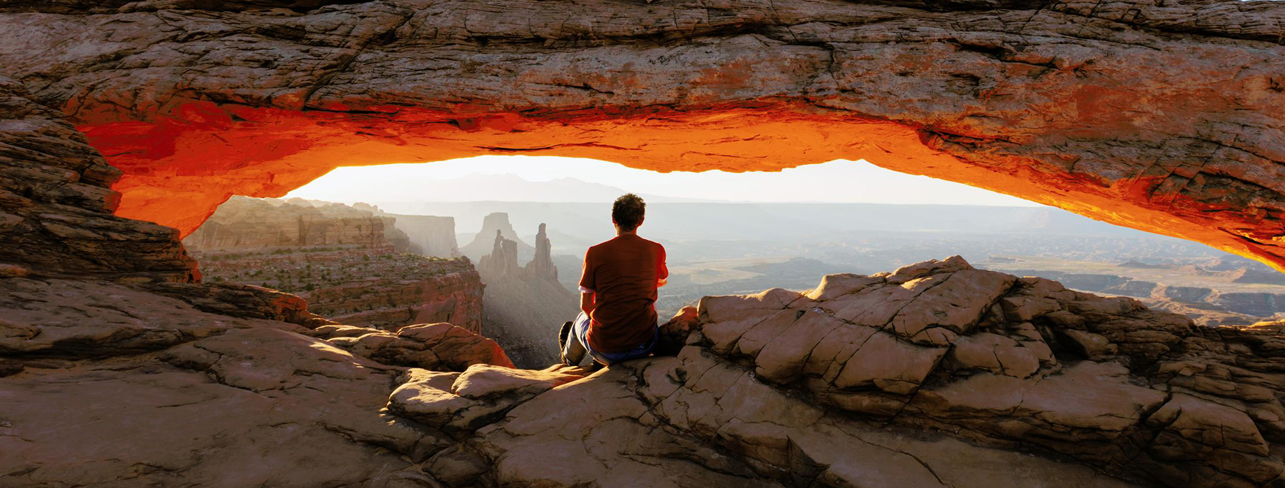 A hiker sitting on a rock gazing out into a canyon