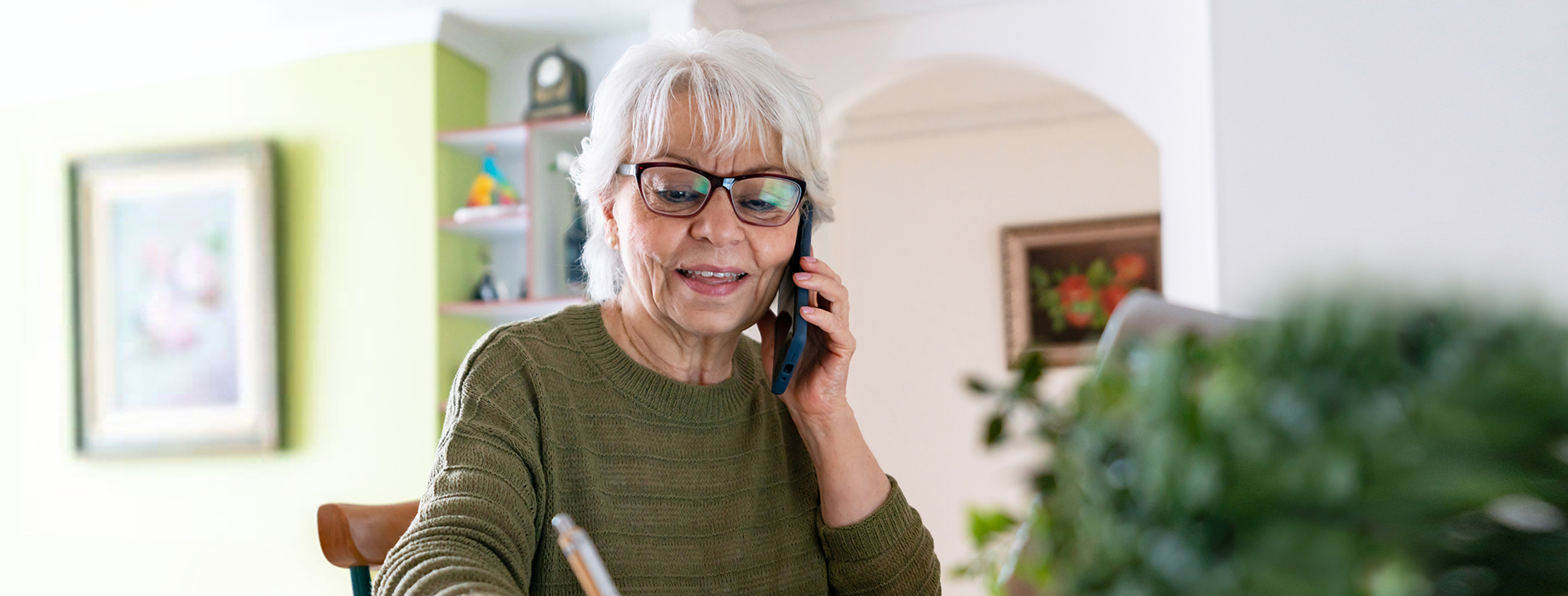 An older woman talking on the phone in front of her computer