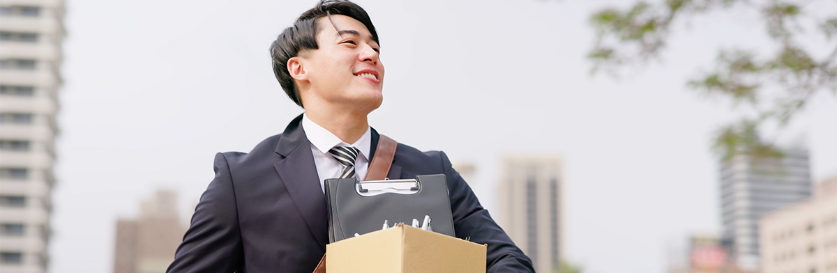 A suited man holds a box, appearing focused as he navigates through a business environment.