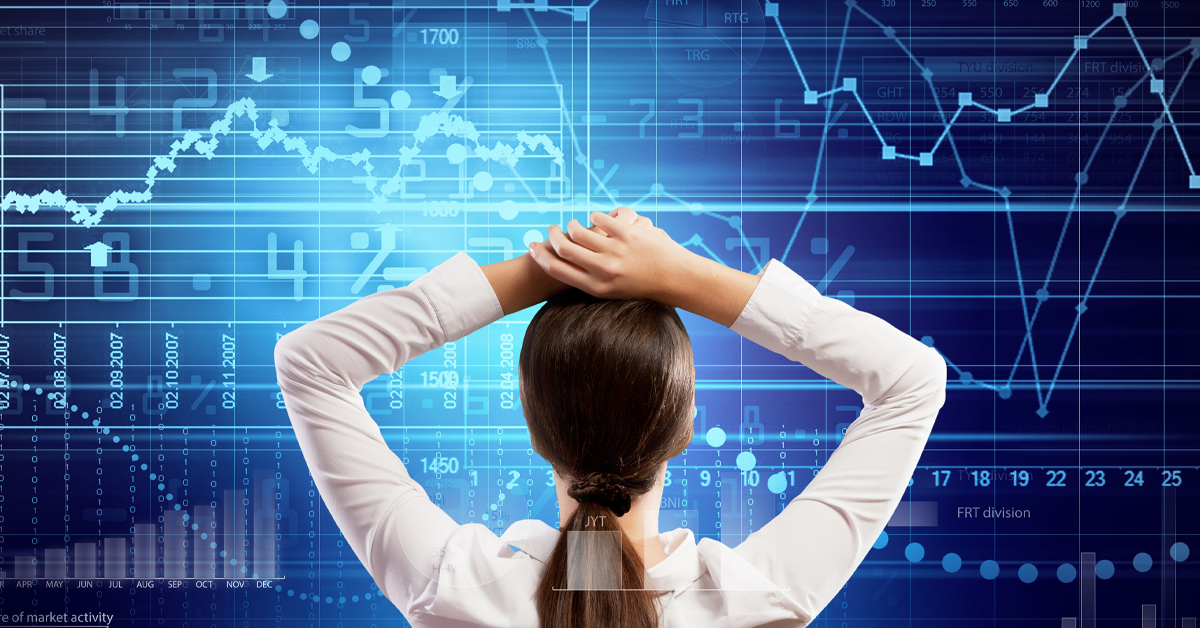 Woman with hands on her head looking at a graph of financial markets on a large screen